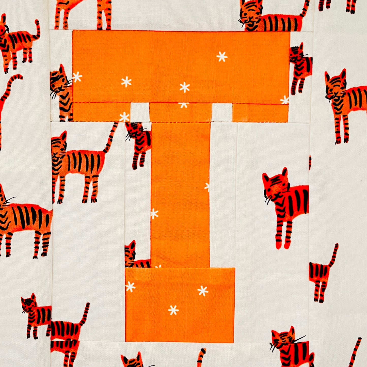 Varsity letter T quilt block in school team colors orange with a tiger print fabric - foundation paper piecing
