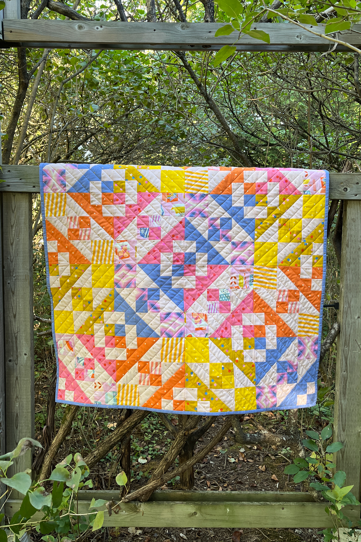 Bright baby quilt on a moody forest gate