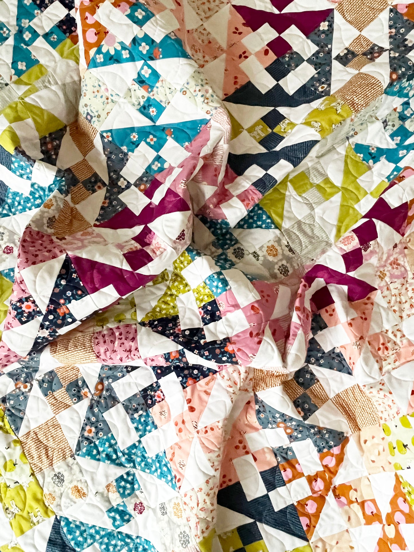 Crumpled patchwork quilt with geometric patterns and contrasting colors.
