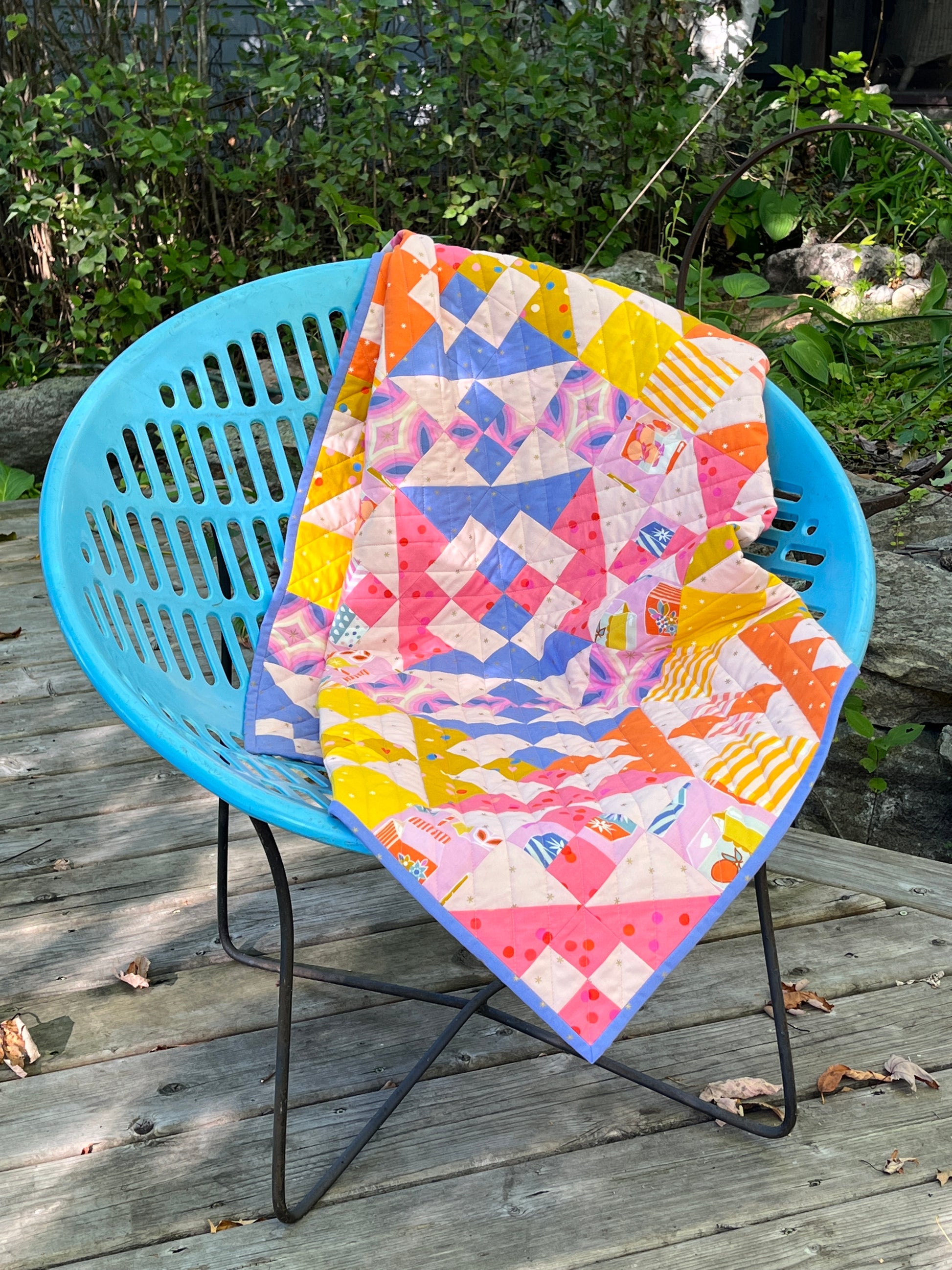 Neon bright baby quilt across a retro blue motel chair