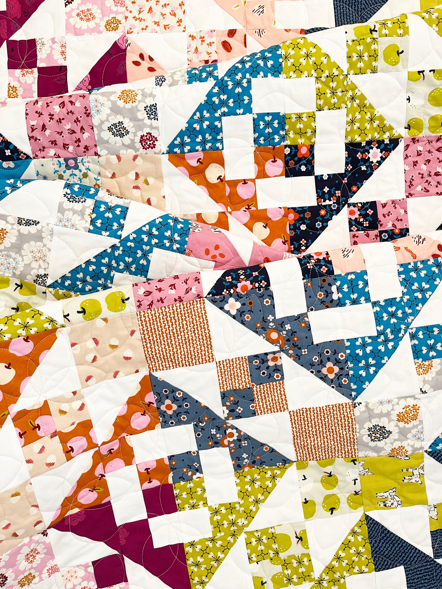 A close-up of a quilt with a vintage-inspired patchwork pattern, featuring a variety of colorful fabric squares and triangles.