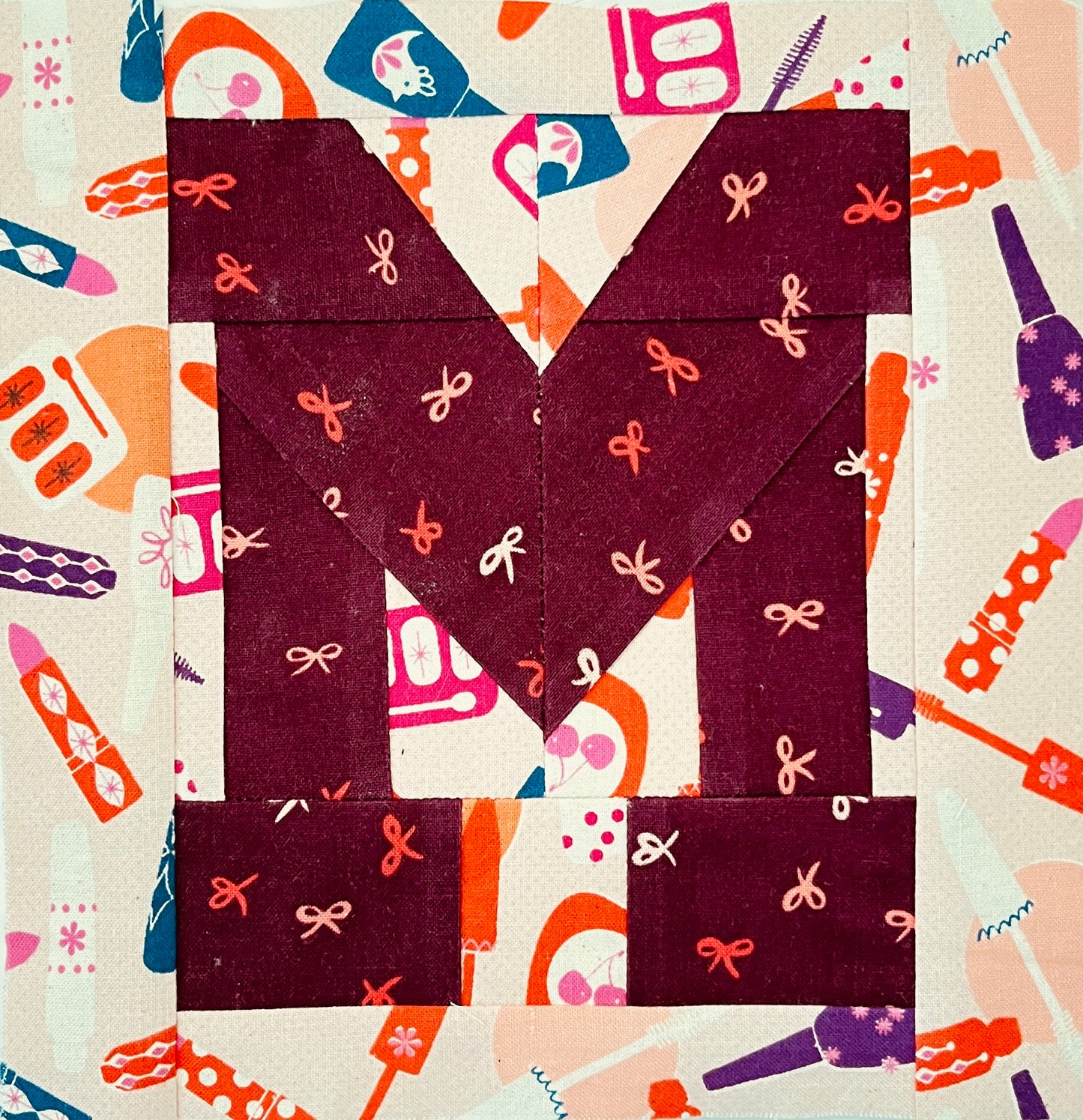 Paper piecing varsity letter quilt block detail M with makeup print background